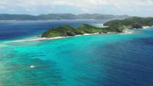 浅いリーフの向こうに横たわる島と、白い砂の線