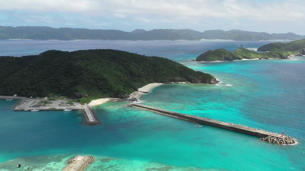 座間味の集落と港、防波堤。浜のすぐ隣に生活がある（ドローンによる空撮）