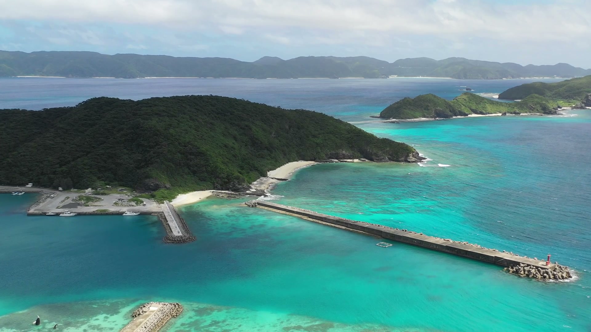座間味の集落と港、防波堤。浜のすぐ隣に生活がある(ドローンによる空撮)
